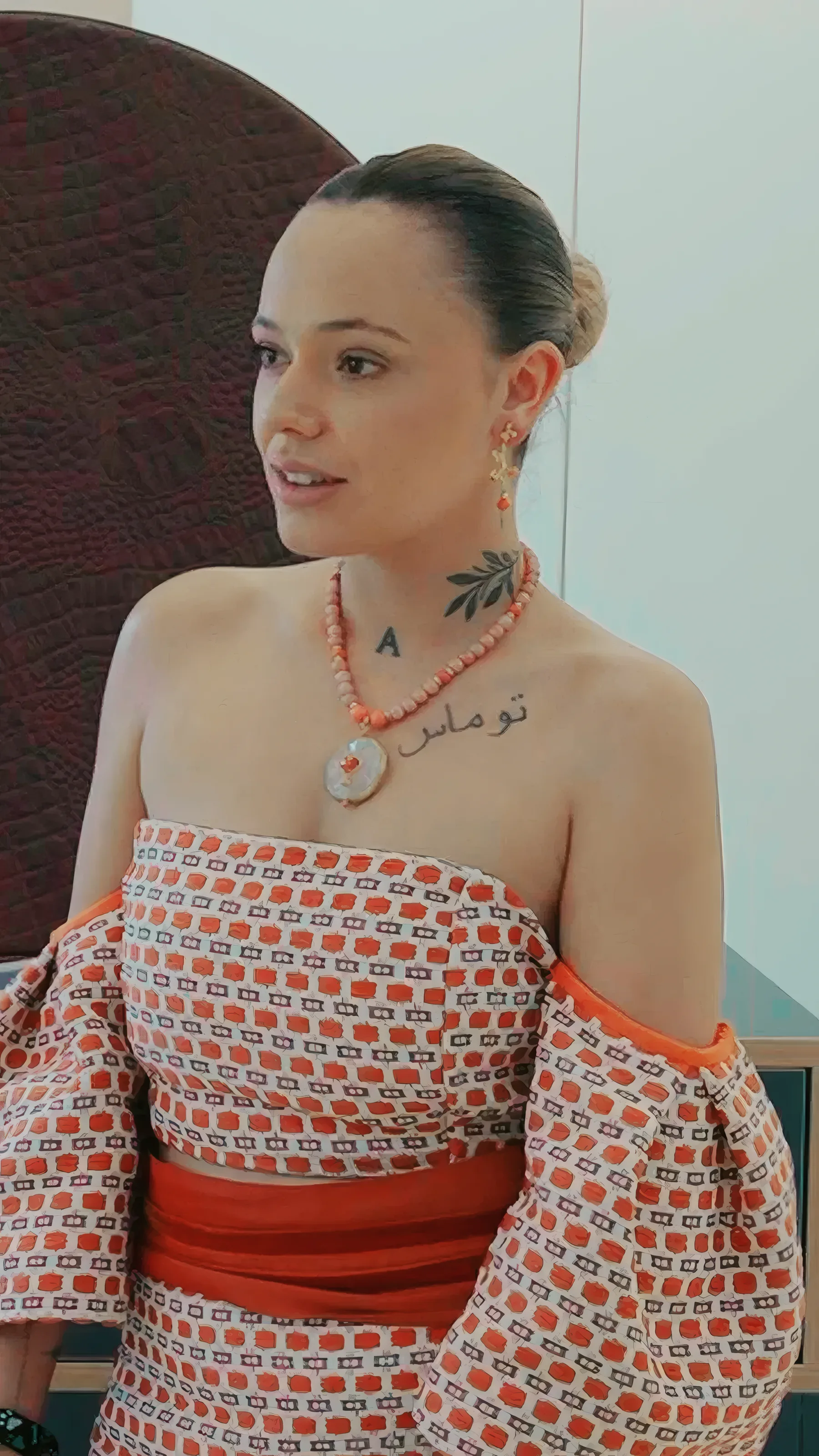 La modelo con el collar de cuentas rojas y el colgante de disco puestos