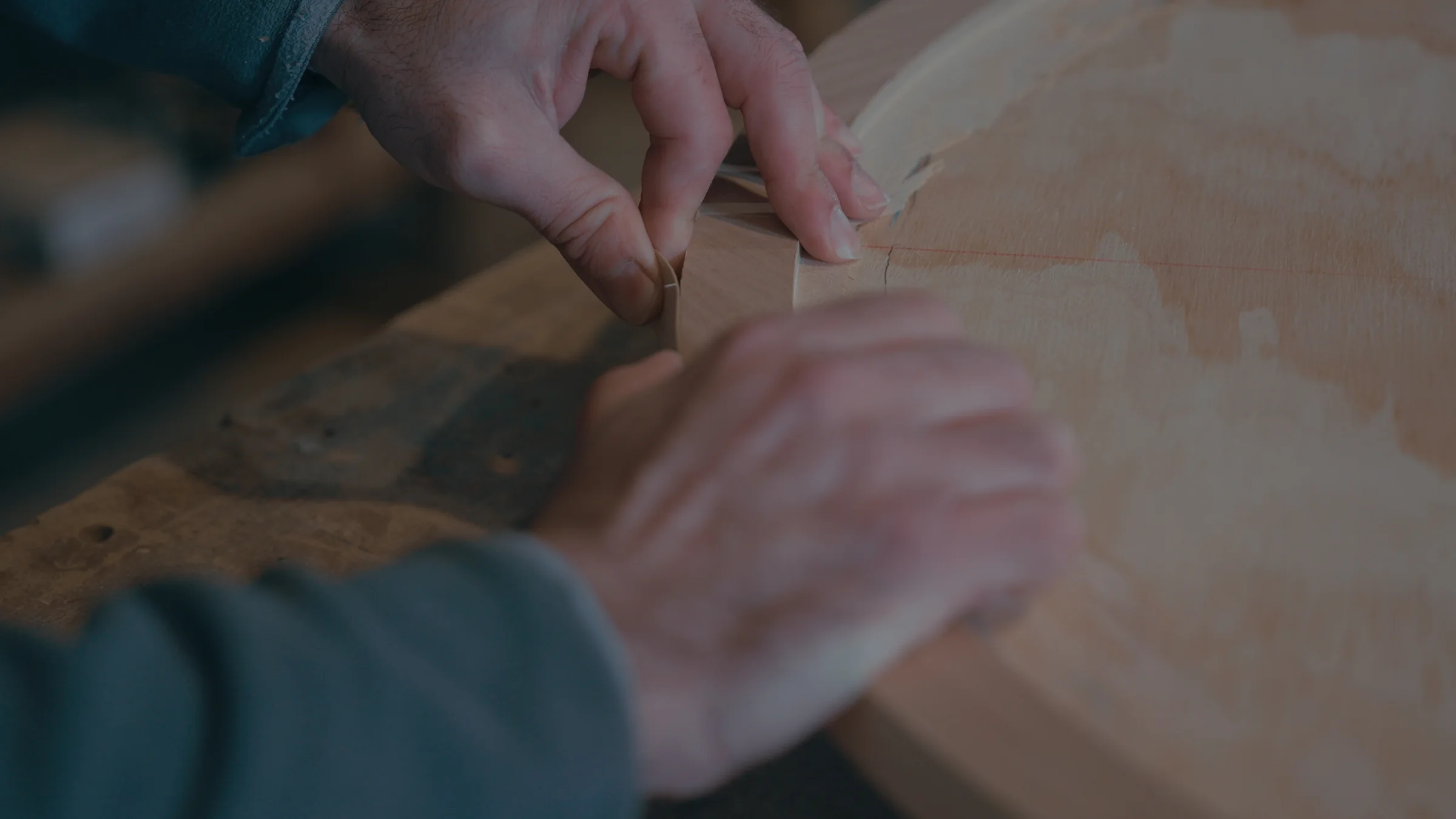 Manos que repasan a mano el canto de una pieza de madera
